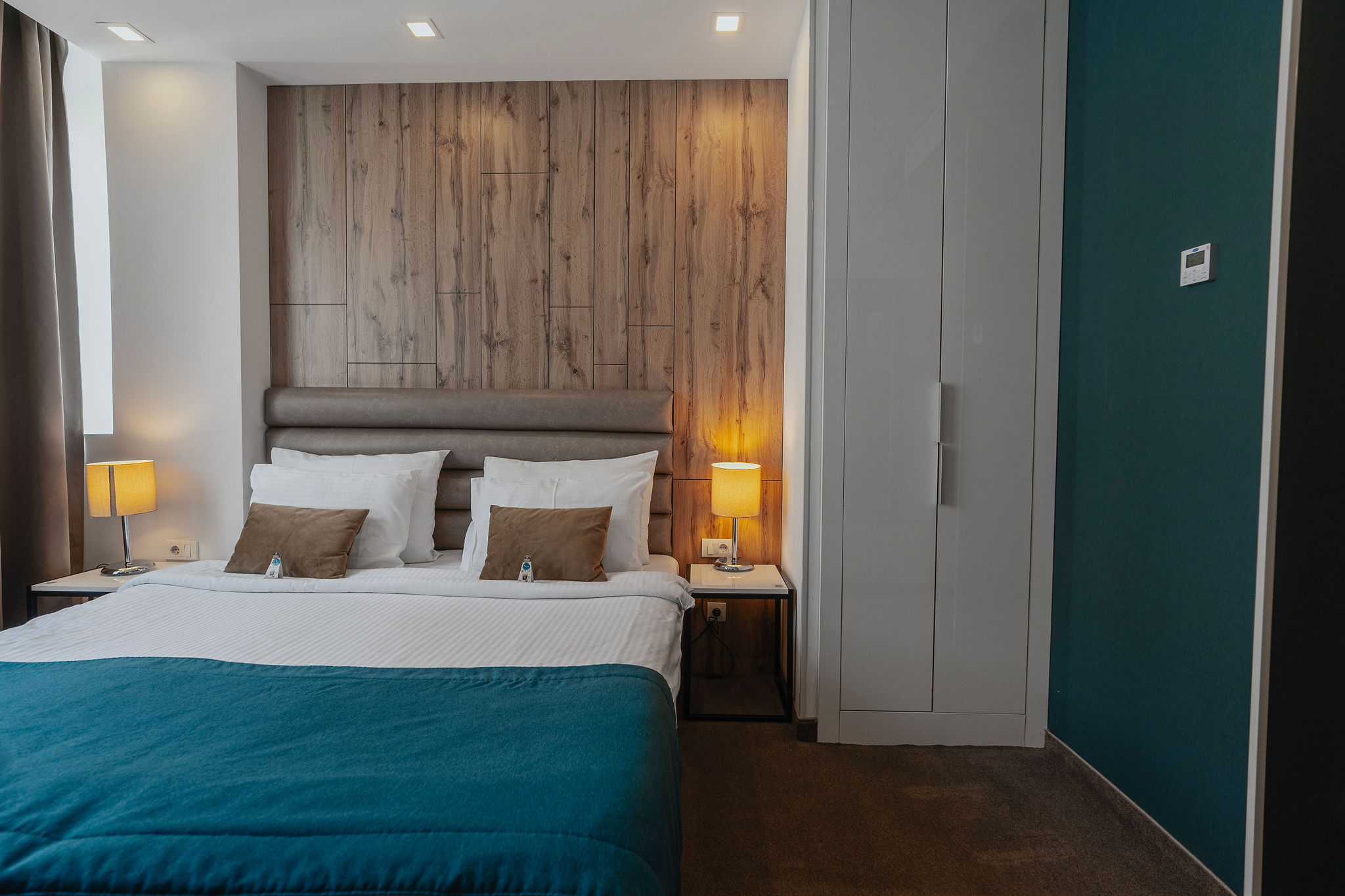 a hotel room bed next to a wardrobe